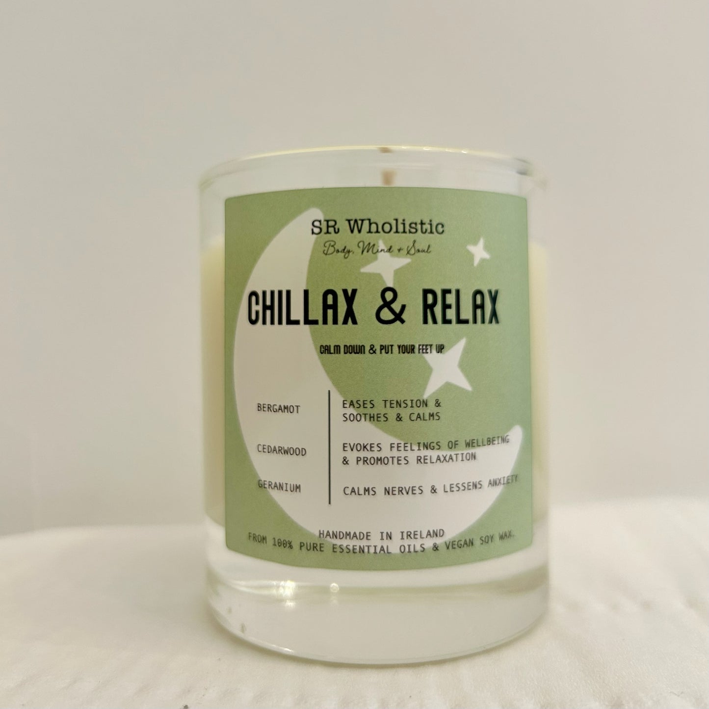 "Chillax & Relax candle in a clear glass jar with label visible, standing alone on a neutral background."