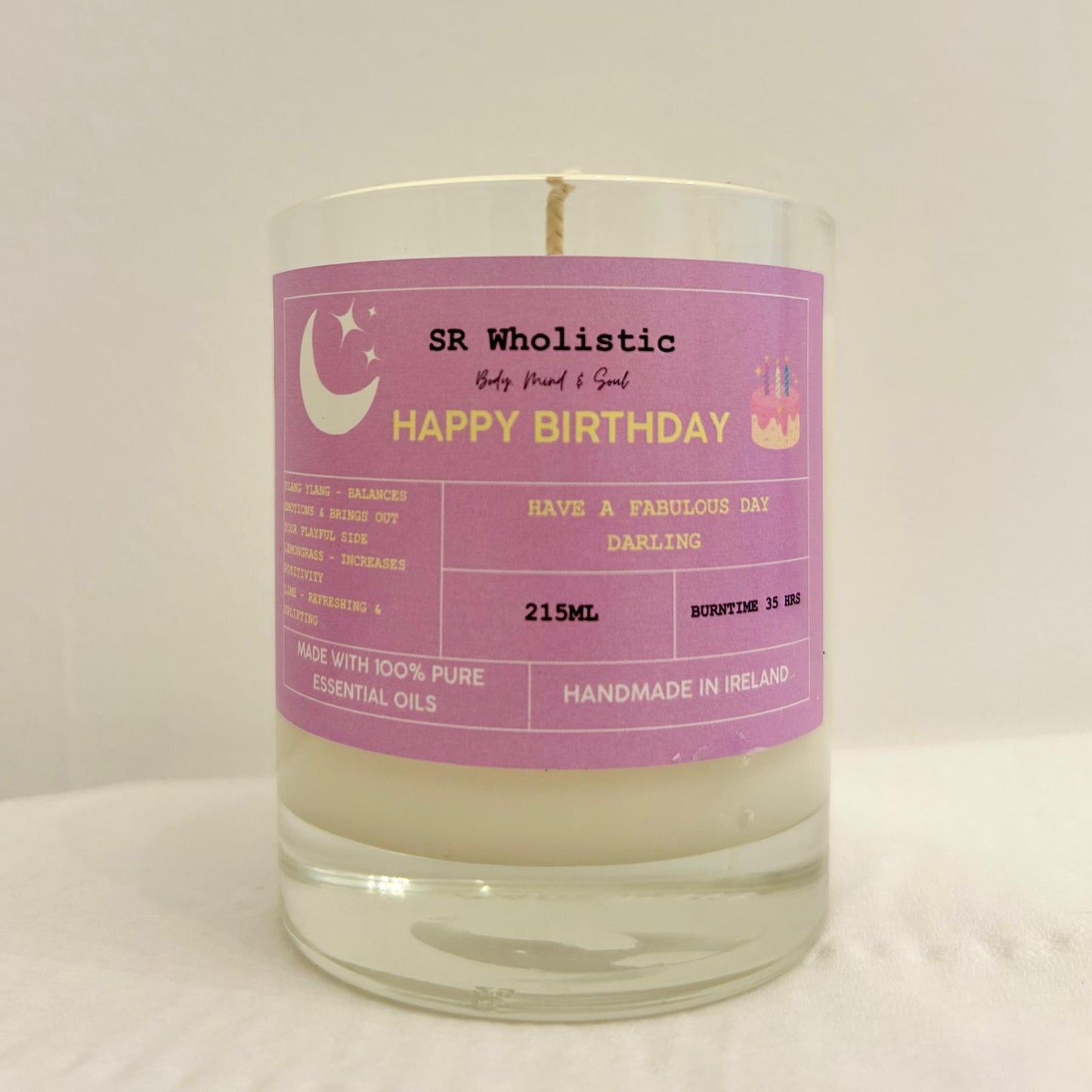 "Happy Birthday candle in a clear glass jar with label clearly visible, standing alone on a neutral background."