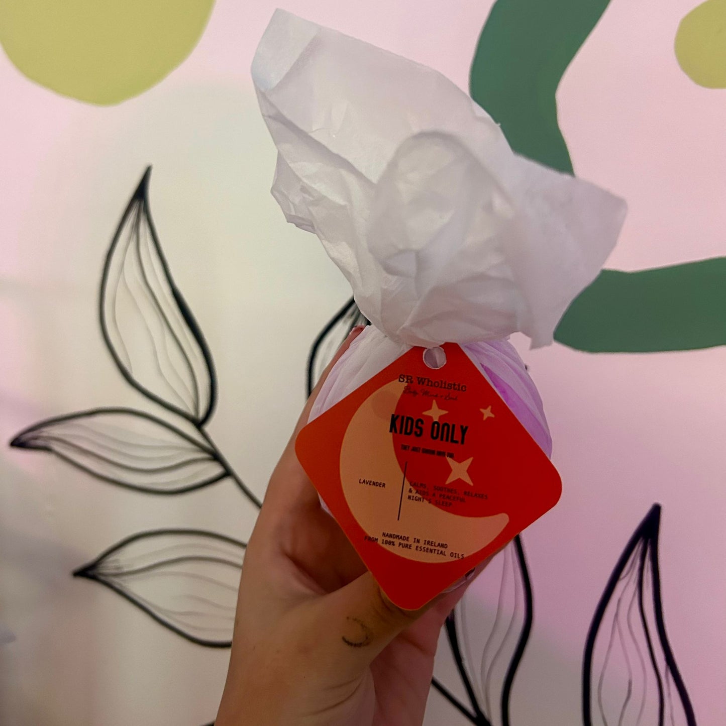 "A brightly colored rainbow Kids Only Bath Bomb with a white tag displaying the product name; made with 100% natural ingredients and gentle lavender essential oil, perfect for sensitive skin."
