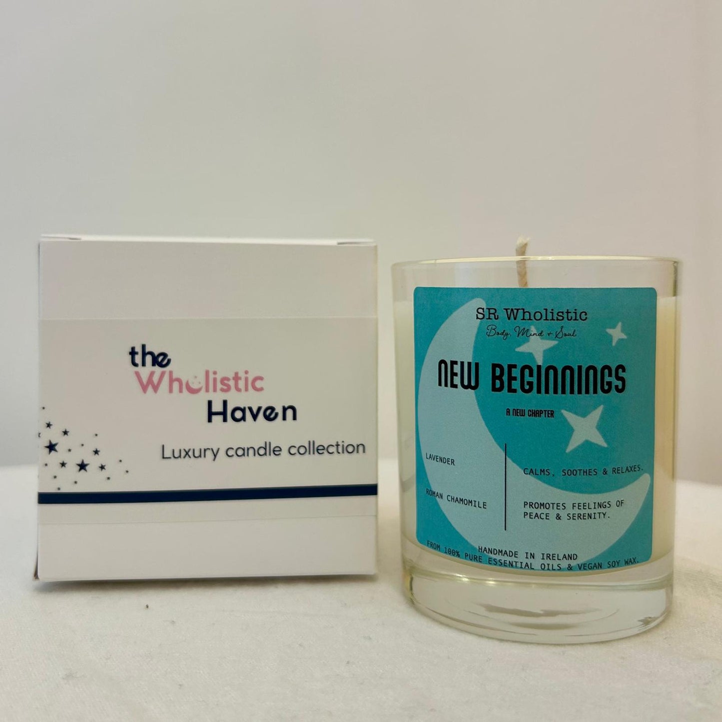 "New Beginnings candle positioned beside its branded packaging box on a clean, serene surface."