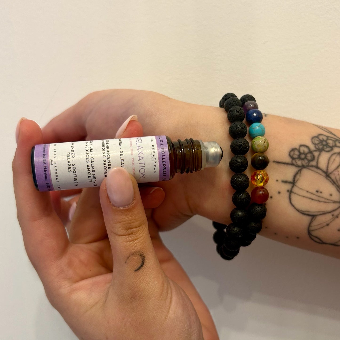 A hand gently rolling the blend onto the inner wrist or pop it on your lava beads for an uplifting scent throughout the day!