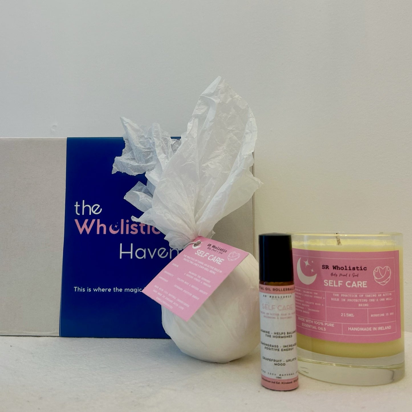 "Self-care gift set featuring a kraft box alongside a jasmine, grapefruit, and lemongrass scented candle, bath bomb, and essential oil rollerball blend – perfect for uplifting and refreshing rituals."