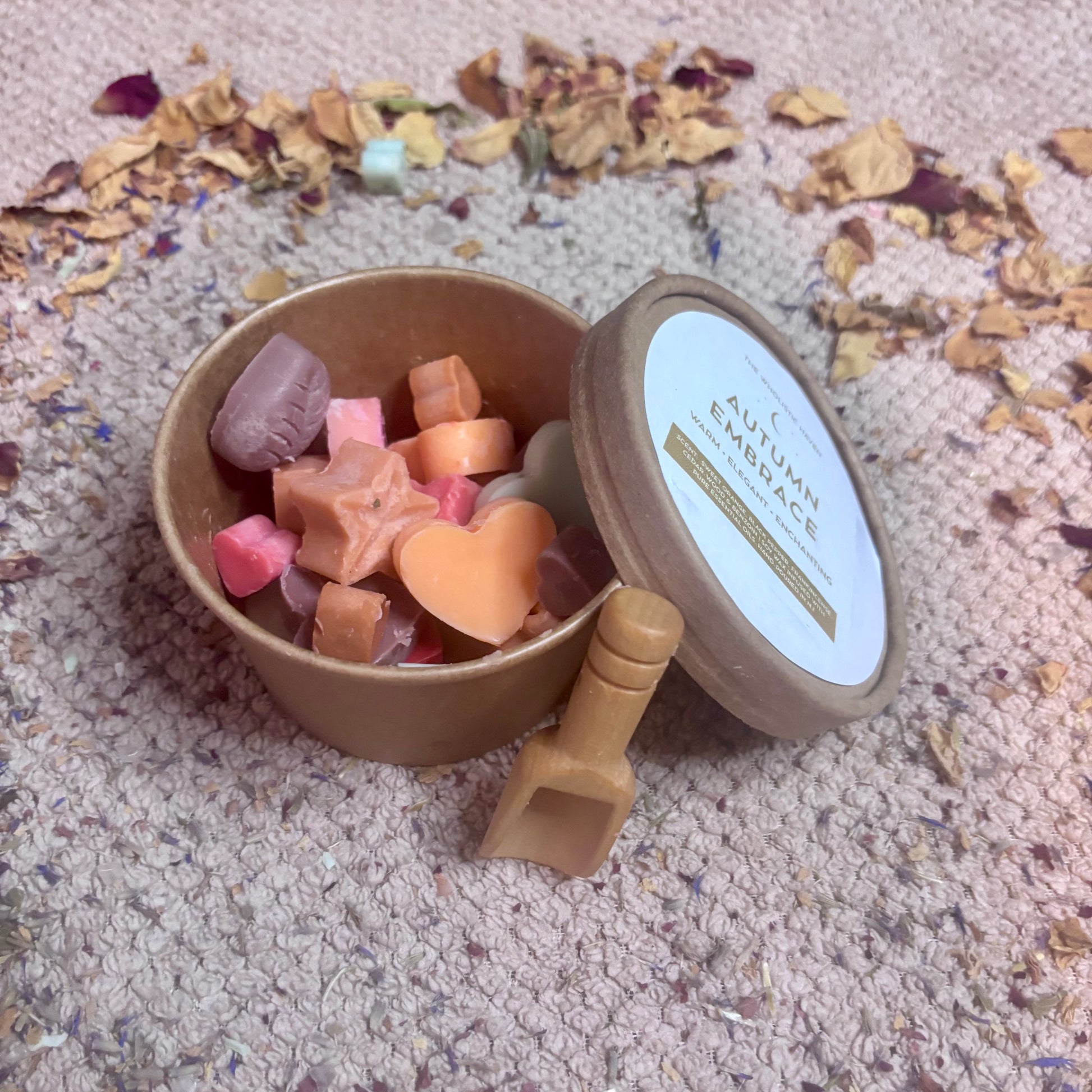 Autumn Embrace wax melts in recyclable tub with wooden scoop, autumnal colours and shapes