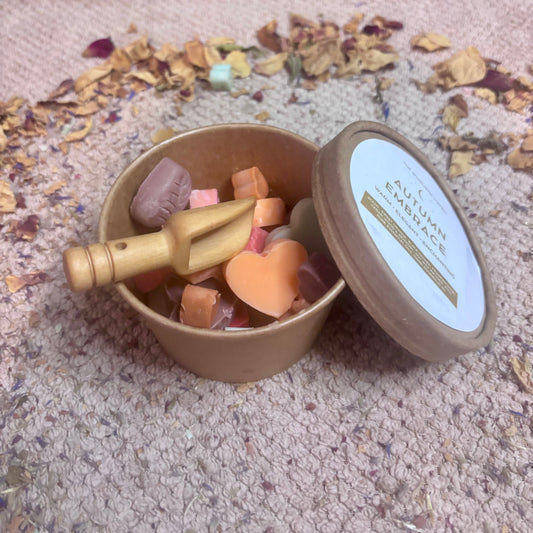 Autumn Embrace wax melts in recyclable tub with wooden scoop, autumnal colours and shapes