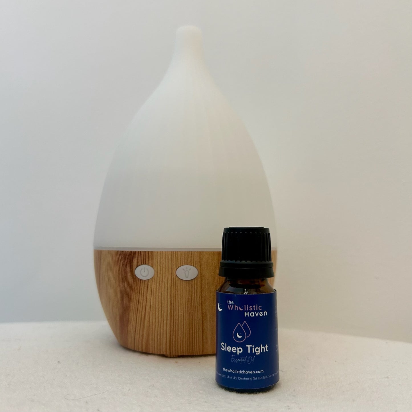 essential oil blend bottle next to a diffuser releasing aromatic mist