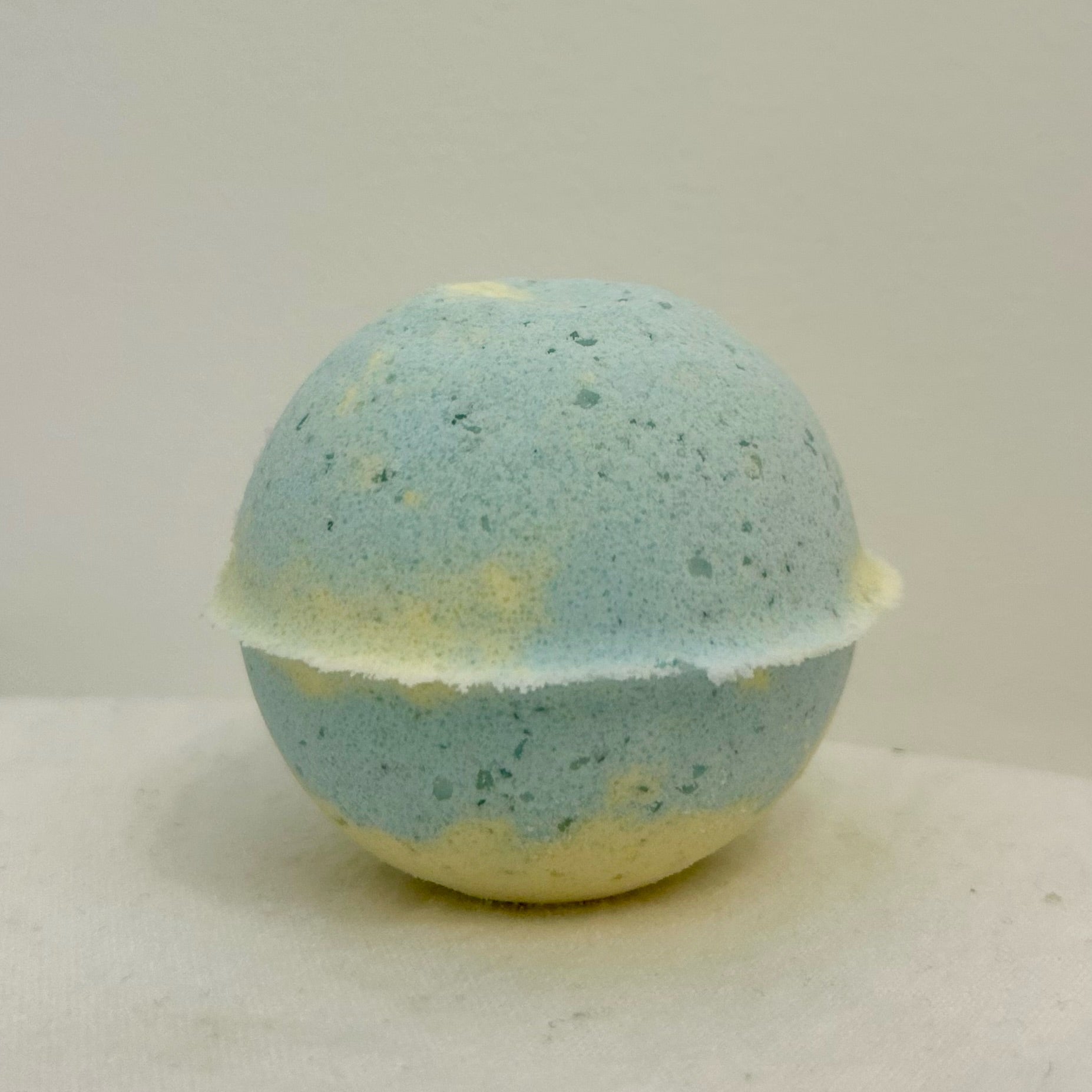 "A close-up of the Happiness Bath Bomb, handcrafted with a natural texture and bursting with the joyful scents of jasmine, lavender, orange, and lemongrass essential oils."
