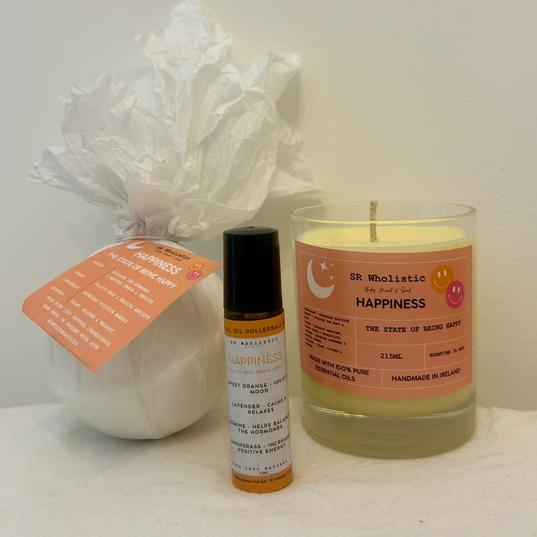 "Happiness Gift Set products laid out in a bright, refreshing flat lay, featuring a candle, bath bomb, and rollerball infused with jasmine, lemongrass, lavender, and orange essential oils."