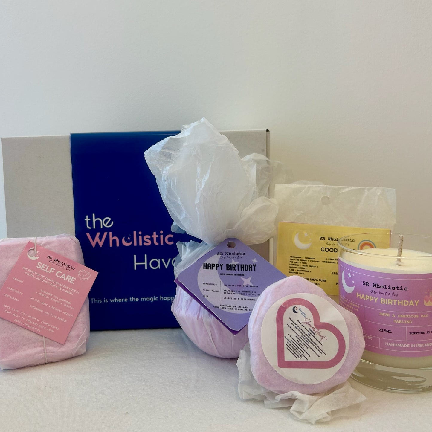 "Happy Birthday Gift Set displayed beside a festive gift box, featuring a vibrant collection of candle, bath bomb, rollerball, wax melts, and shower bomb infused with ylang ylang, lemongrass, and lime essential oils."