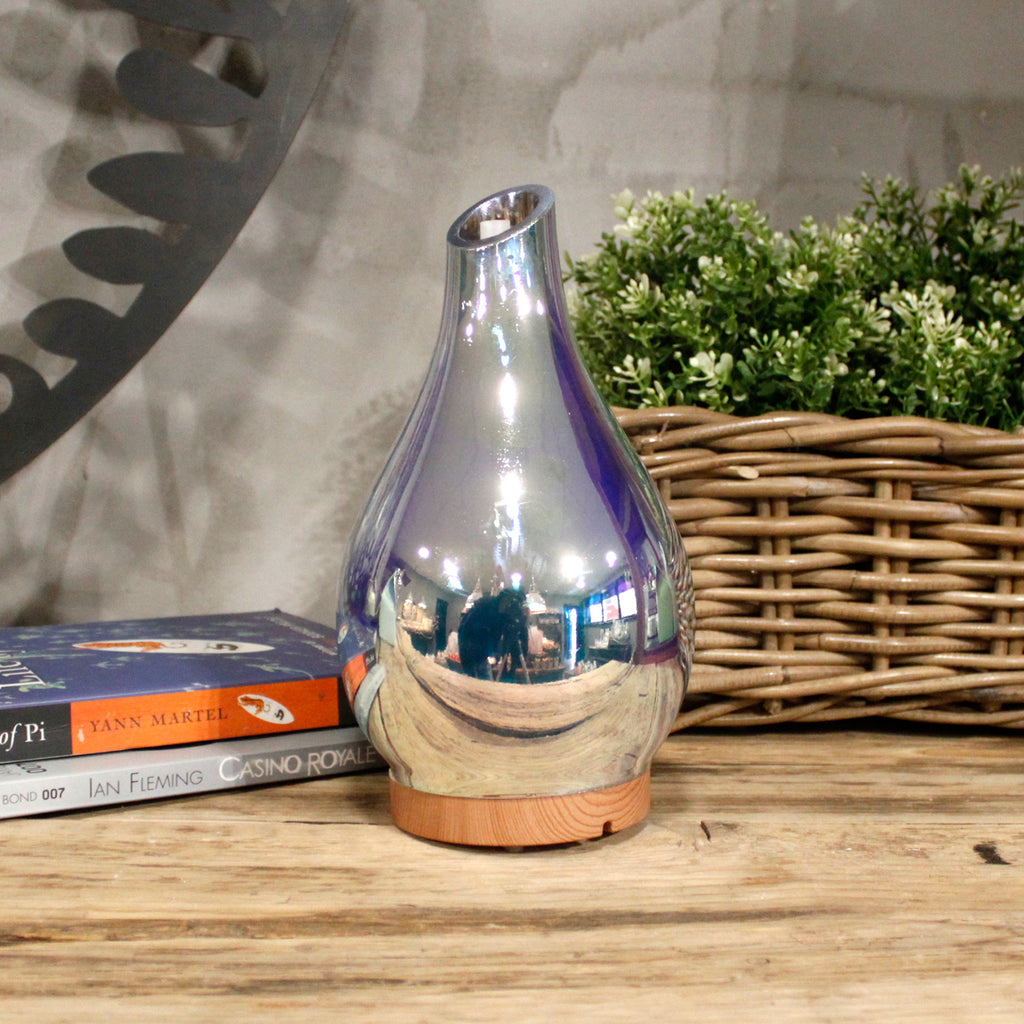 Silver reflective vase on a wooden surface with books and a basket in the background