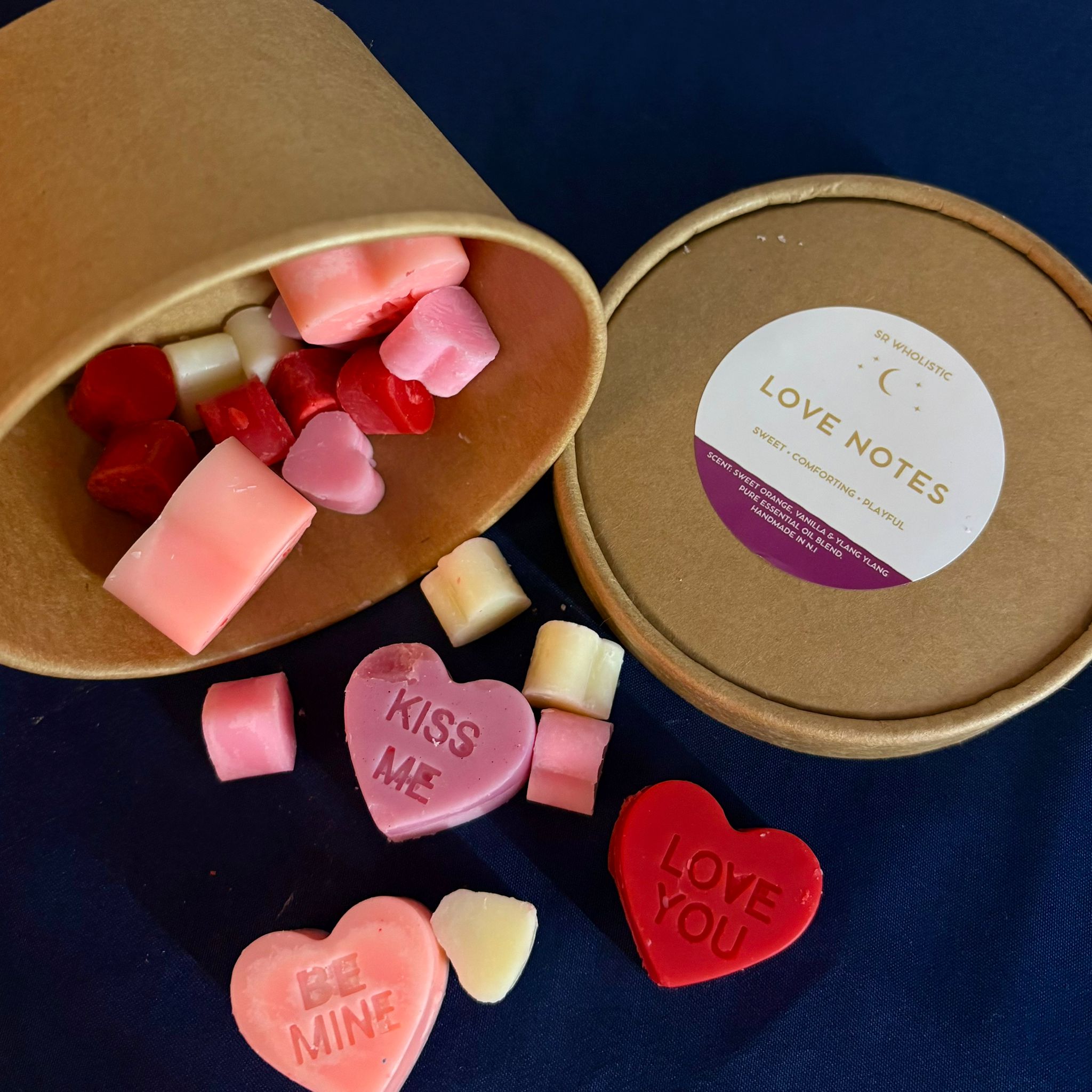 Heart-shaped wax melts in a Kraft container with 'Love Notes' label on a dark blue background