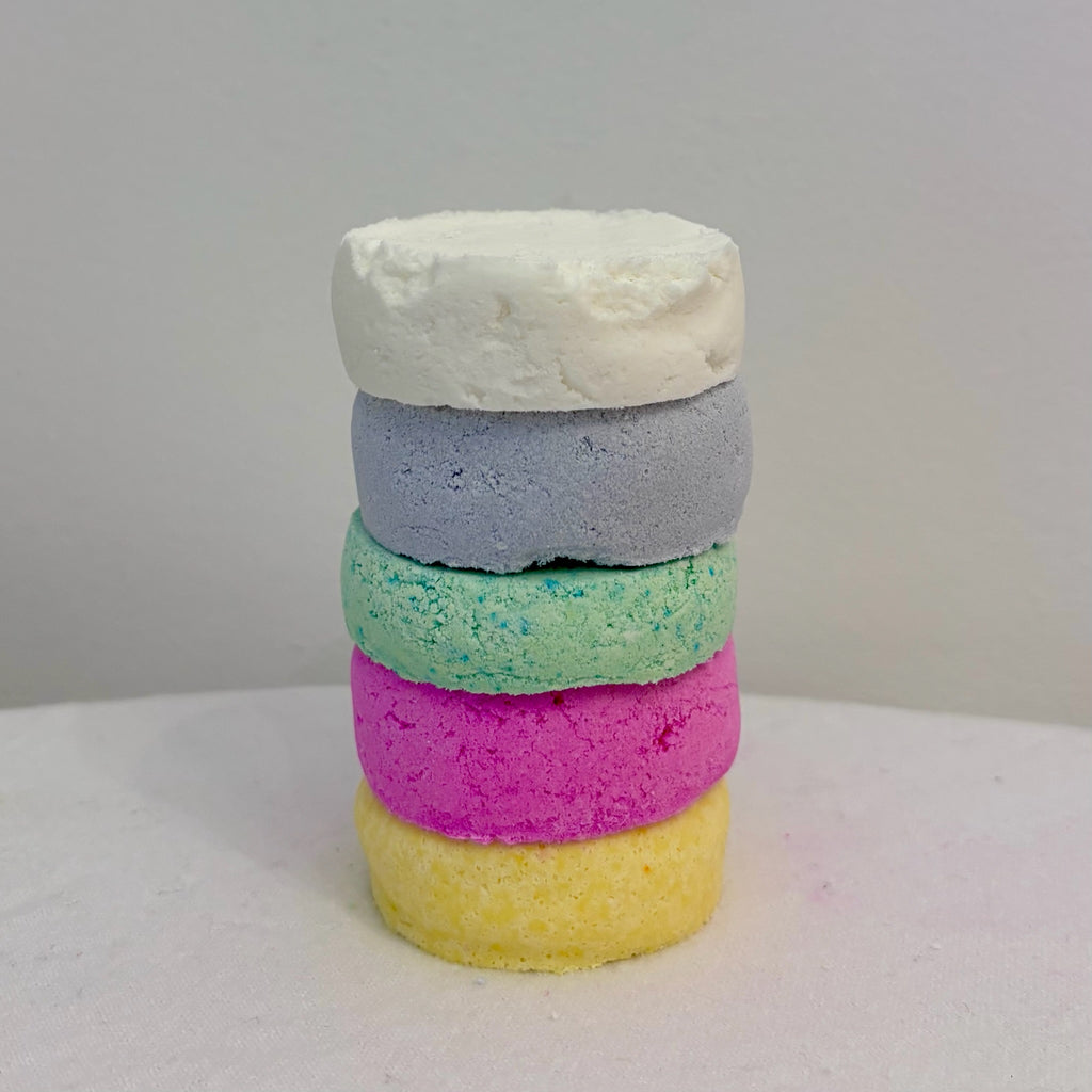 Stack of five multicoloured shower bombs in vibrant pastel tones, showcasing variety of scents