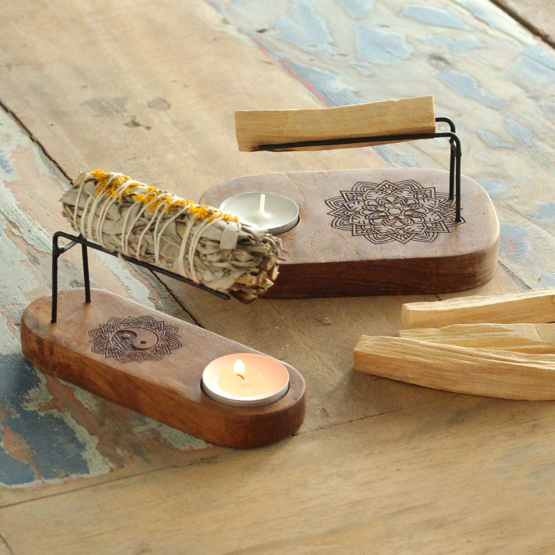 Wooden incense burner with candles and sticks on a textured surface