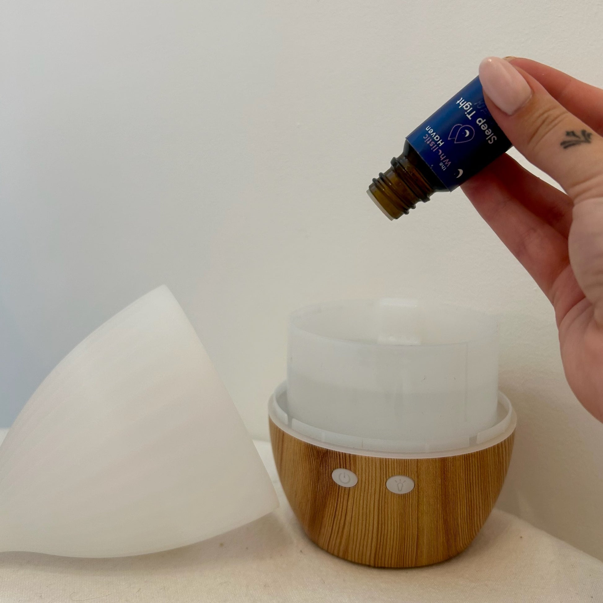 Hand adding drops of Jasmine, Grapefruit & Lemongrass essential oil blend into a diffuser