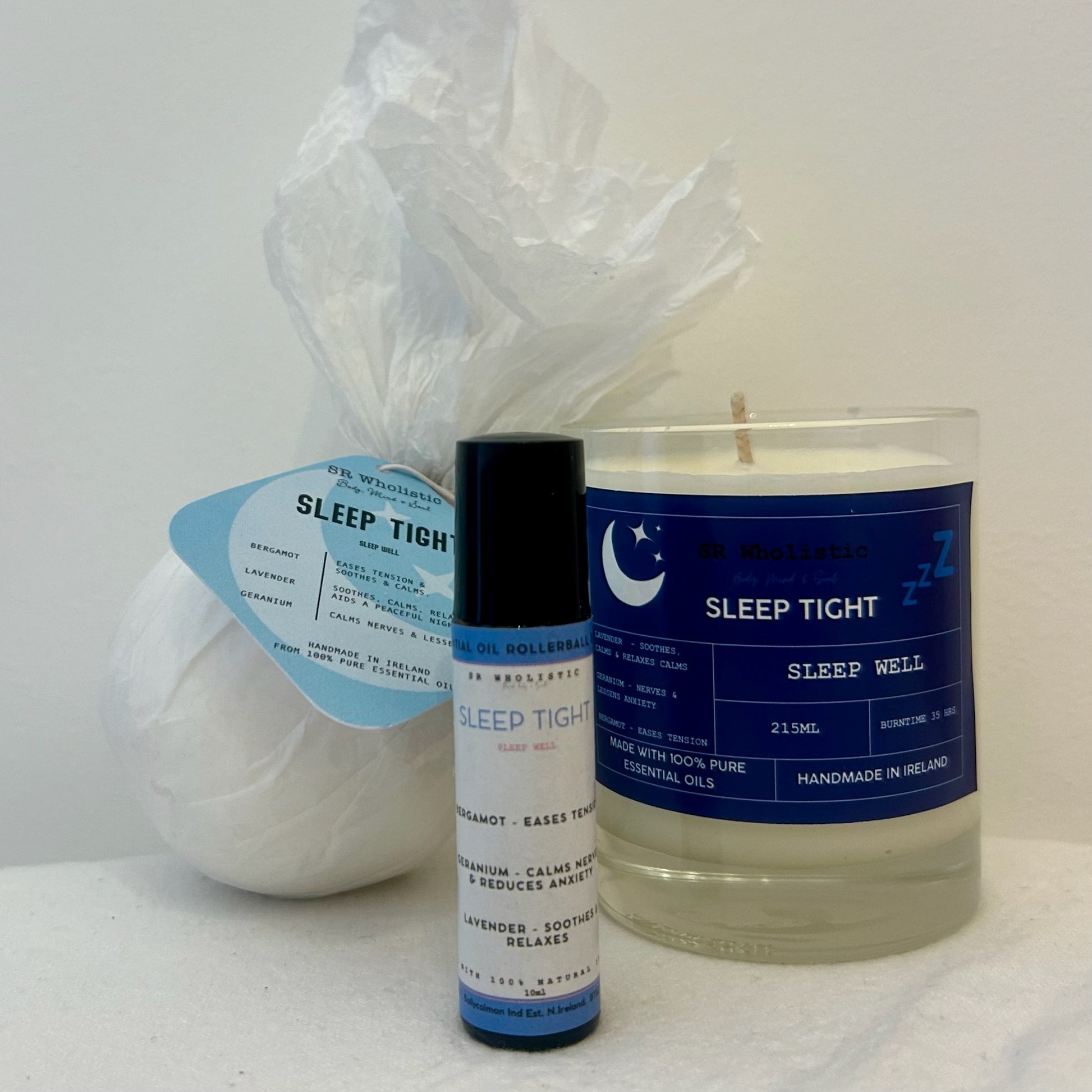 "Sleep Tight candle, bath bomb, and rollerball set styled in a soothing flat lay, made with a peaceful blend of lavender, geranium, and bergamot for deep relaxation."