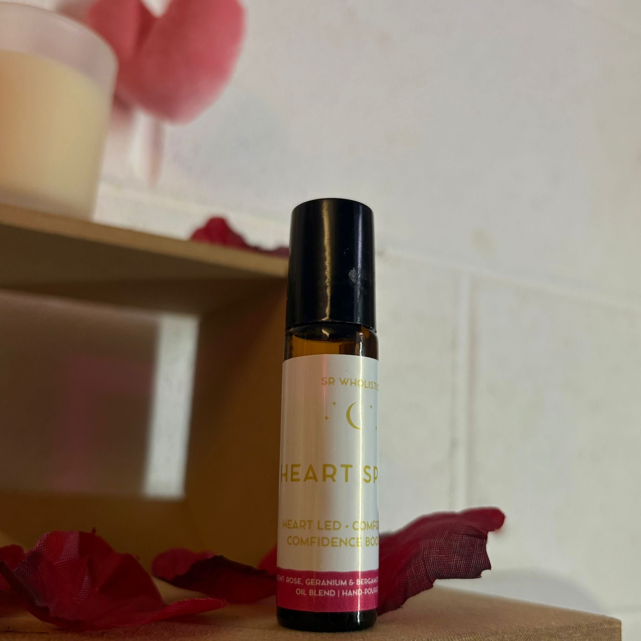 Small bottle labeled 'Heart Space' with red petals on a wooden surface