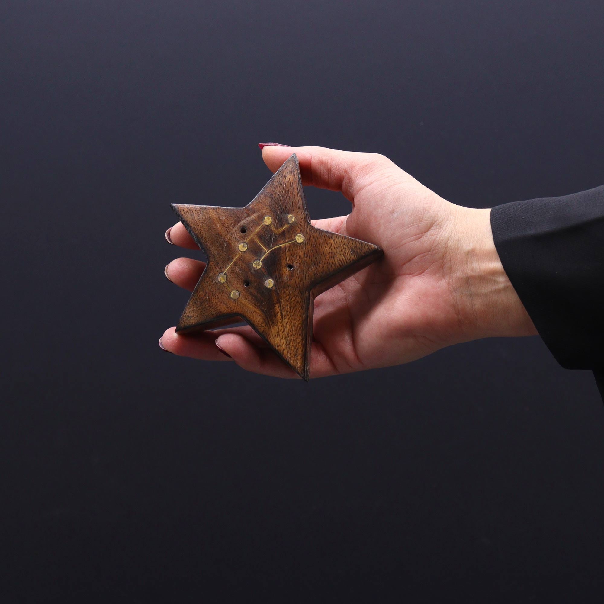 Hand holding a rusty star-shaped object against a dark background