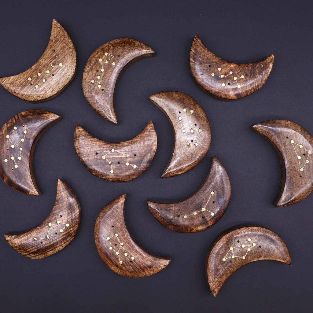 Wooden moon-shaped coasters with star constellations on a dark background