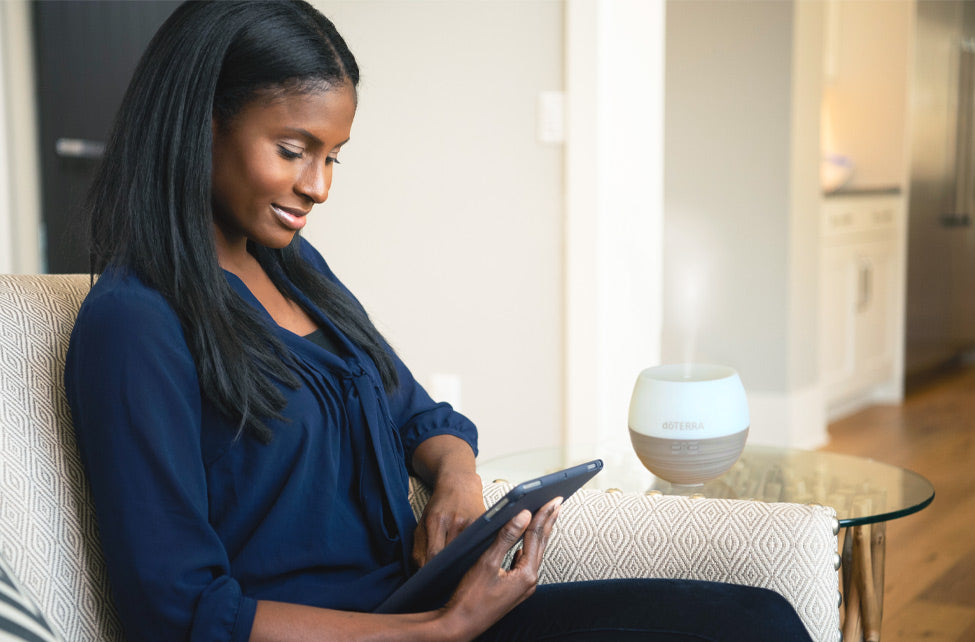 Woman sitting on a couch using a tablet in a modern living room.