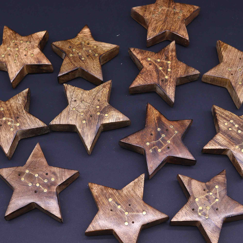 Wooden star-shaped objects with embedded constellations on a dark background